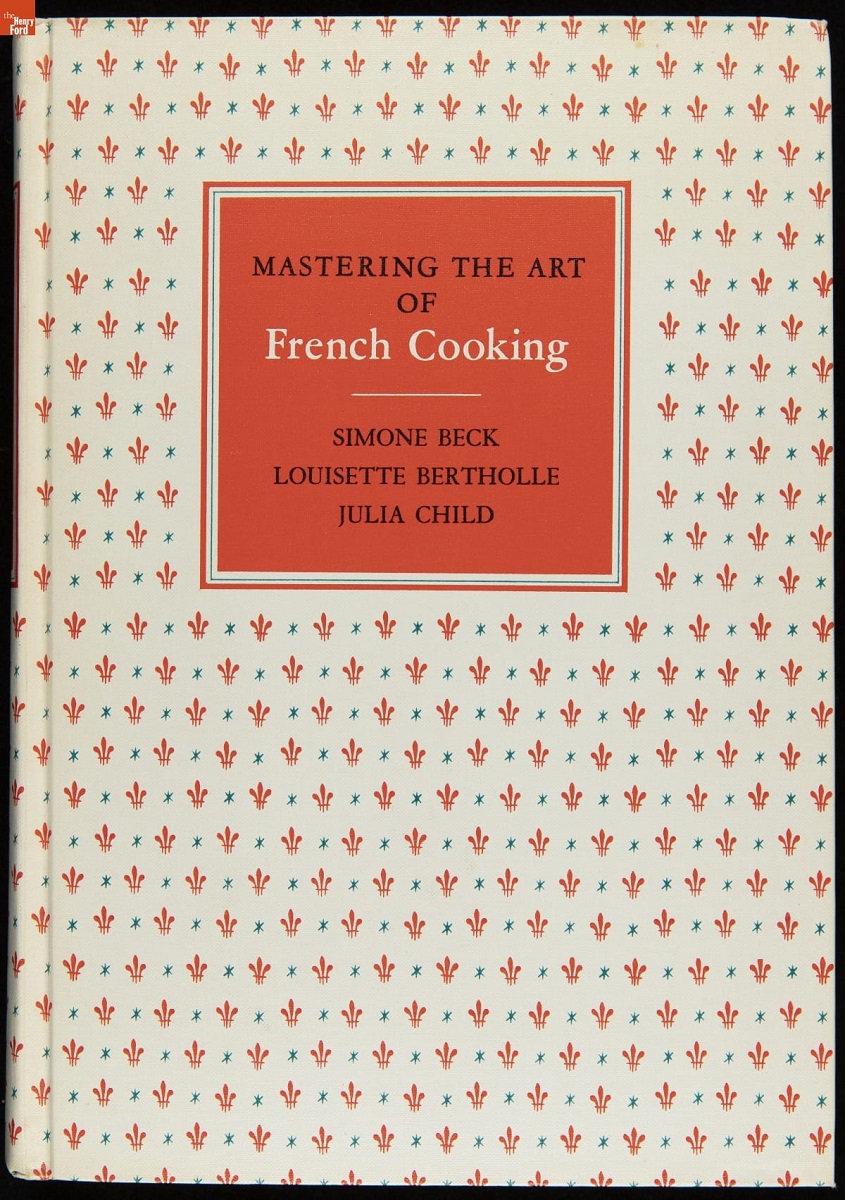 Mastering the Art of French Cooking, 1964 White book cover with text on orange background and pattern of orange fleur-de-lis and blue asterisk-like stars