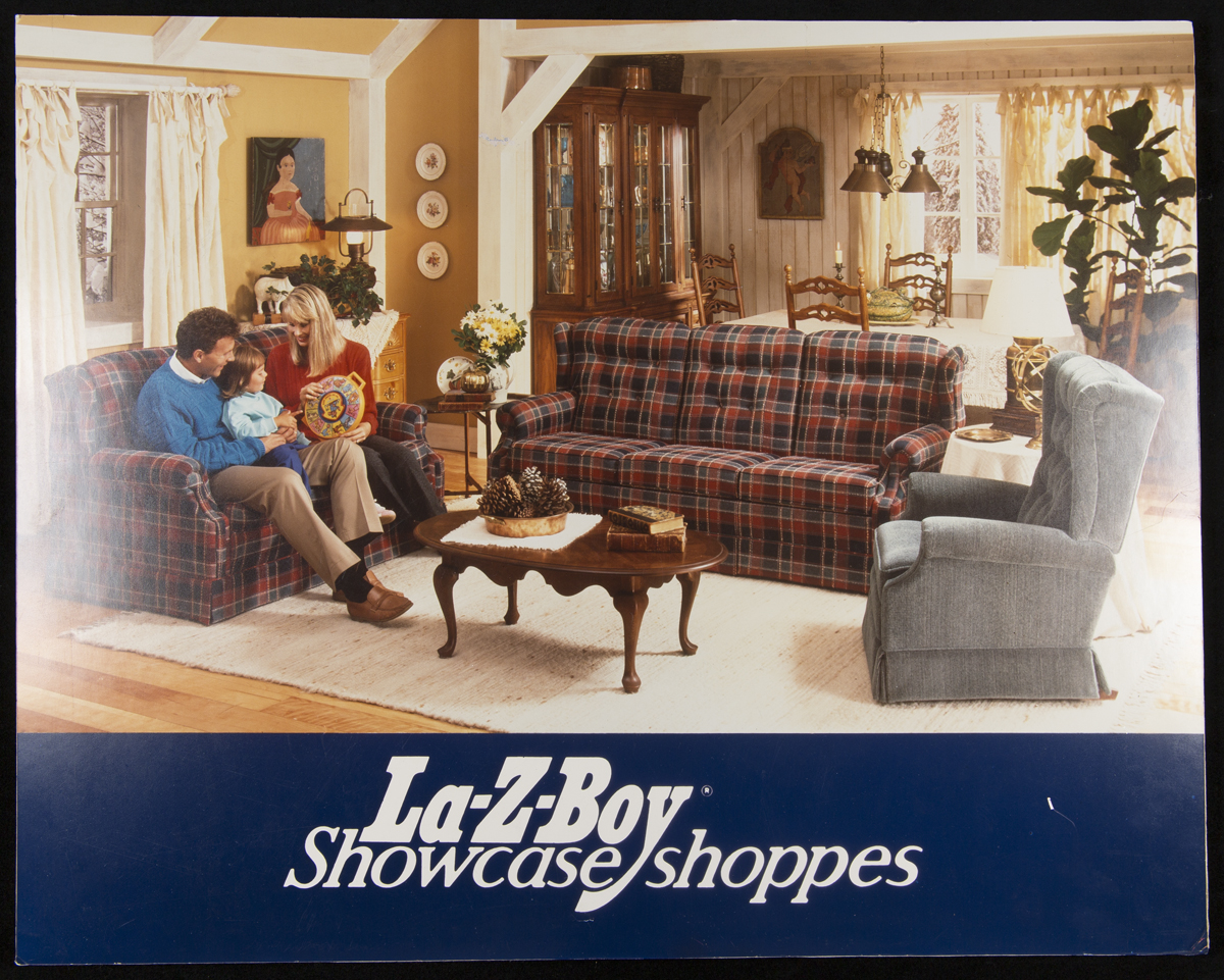 La-Z-Boy Showcase Shoppes, 1980-1988	Living room with woman, man, and child on couch, with text “La-Z-Boy Showcase shoppes” below