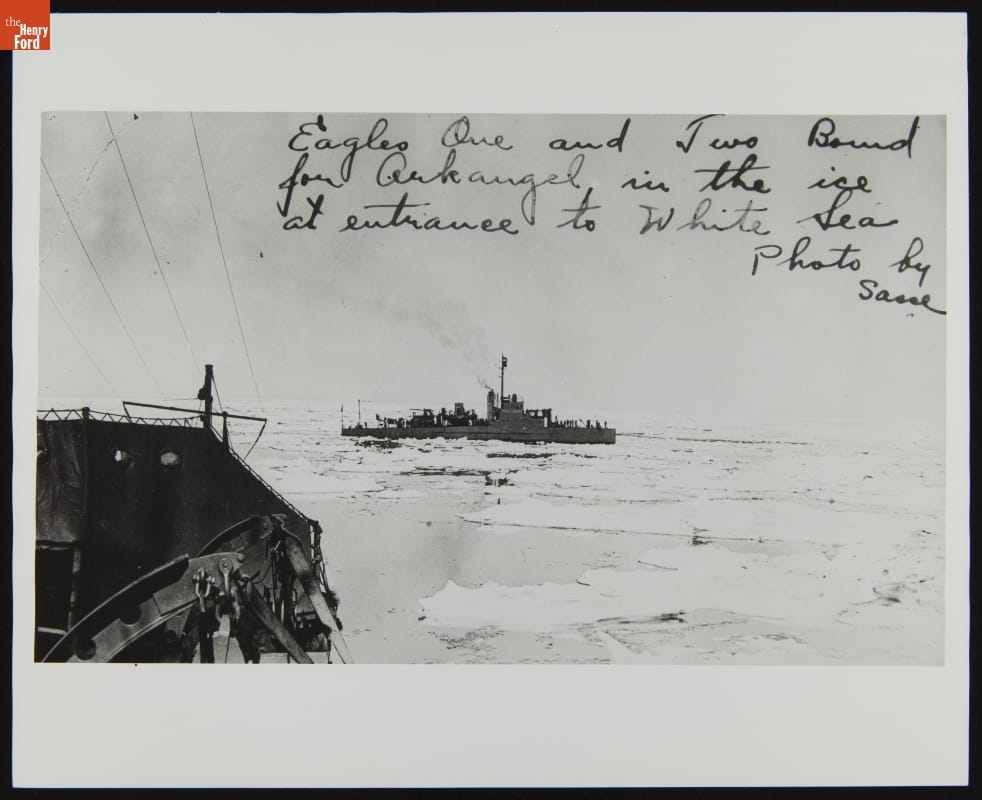 Boat on ice-packed body of water, taken from another ship partially visible in foreground