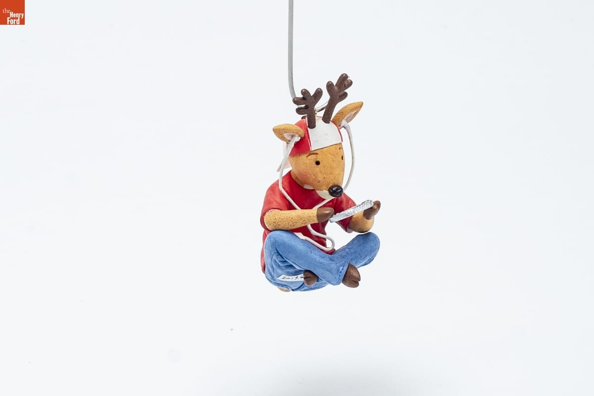 Hallmark "Wired for Fun" Christmas Ornament, 2009 Christmas ornament showing a reindeer wearing a red tshirt, blue jeans, a backwards red-and-white baseball cap, and earphones, sitting cross-legged while looking at a handheld device
