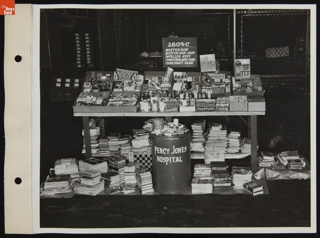 Assorted Gifts for Veterans at Percy Jones Hospital, March 1945 Table piled with small items, books and magazines underneath, along with bin labeled “Percy Jones Hospital”