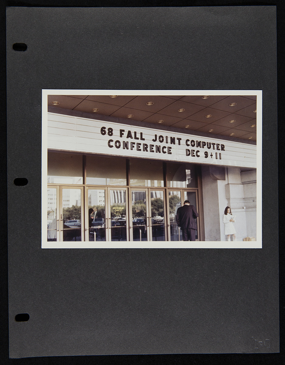 Page from Report on the SRI Fall Joint Computer Conference, December 27, 1968 Three-ring binder black-colored page with a photo of entrance doors and a marquee with text; two people in front of doors