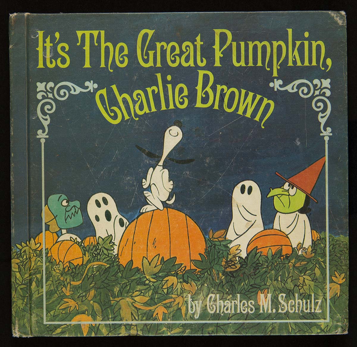 It's The Great Pumpkin, Charlie Brown, 1967 Blue book cover with text and image of children in Halloween costumes in a pumpkin field, watching a dog dancing on a pumpkin