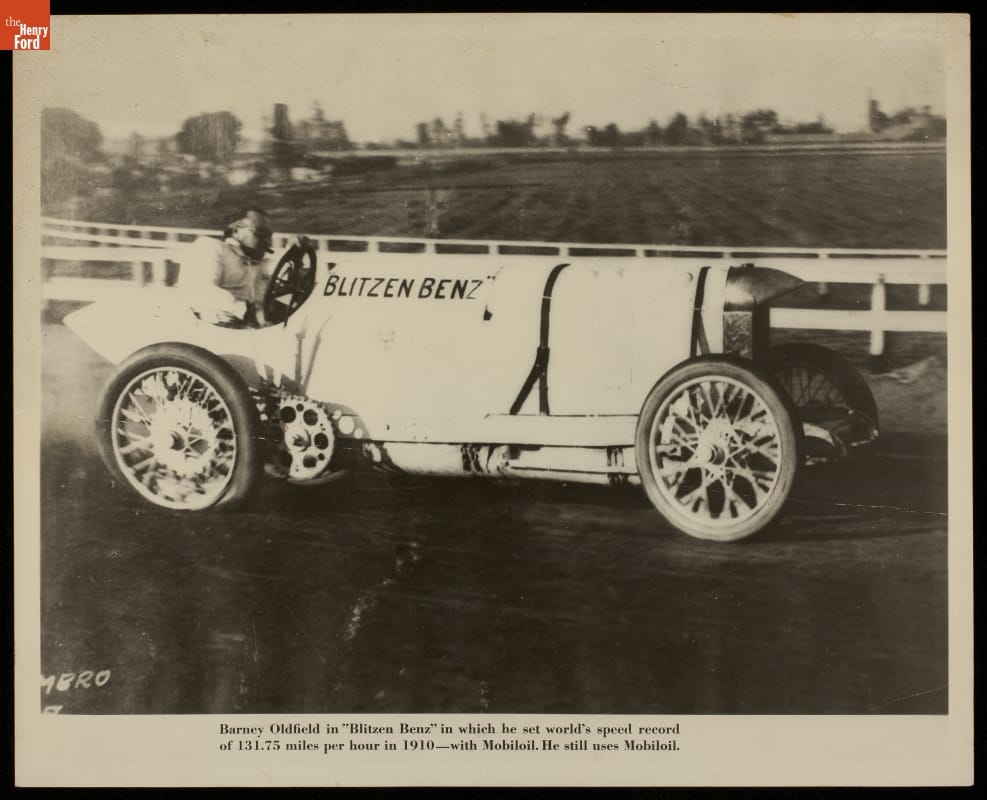 Barney Oldfield Driving the "Blitzen Benz" Car on a Racetrack, 1910 Man behind wheel of early open race car on a track; also contains text