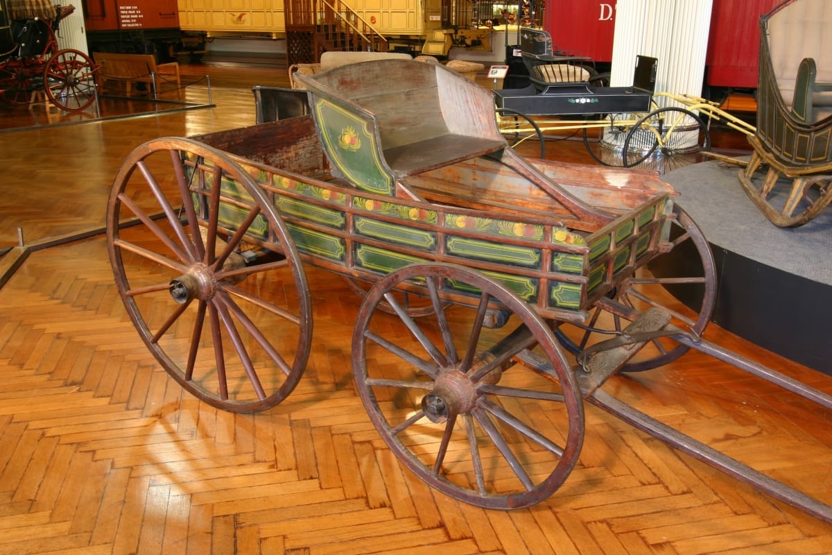 Pleasure Wagon, circa 1820 Open woden wagon painted with decorative pattern in green and other colors, with two large rear wheels and two smaller front wheels