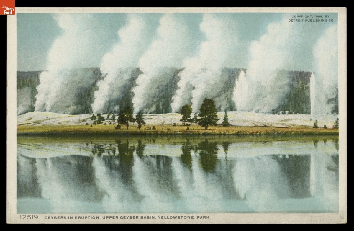 Postcard with text and image of geysers erupting with hills in the background and a lake in the foreground