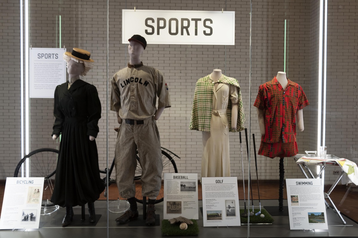 The display case for What We Wore: Sports in Henry Ford Museum of American Innovation Large glass case with large label "Sports," other smaller labels, and four mannequins wearing various clothing