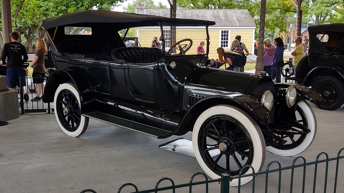 1915 Cadillac V-8 touring car at Old Car Festival 2022 Old-fashioned black car with open sides and dash and whitewall tires, with people standing nearby