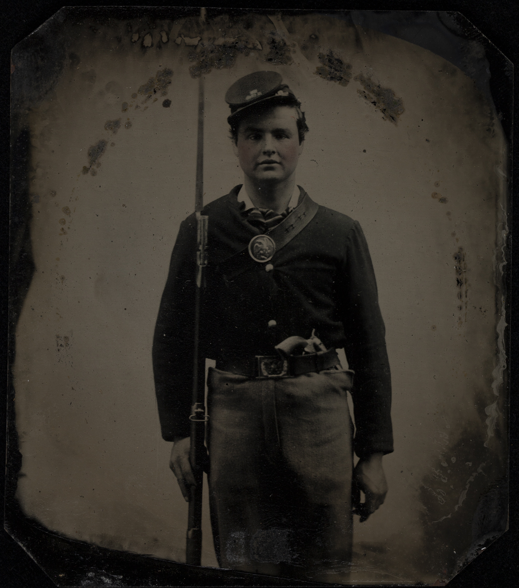Man in uniform and cap holding rifle and standing at attention