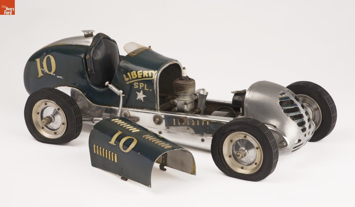 Korn "Liberty Special" Indianapolis Gas-Powered Racing Tether Car, 1940-1941 Long green model car with text and numbers on side, hood removed and sitting next to car