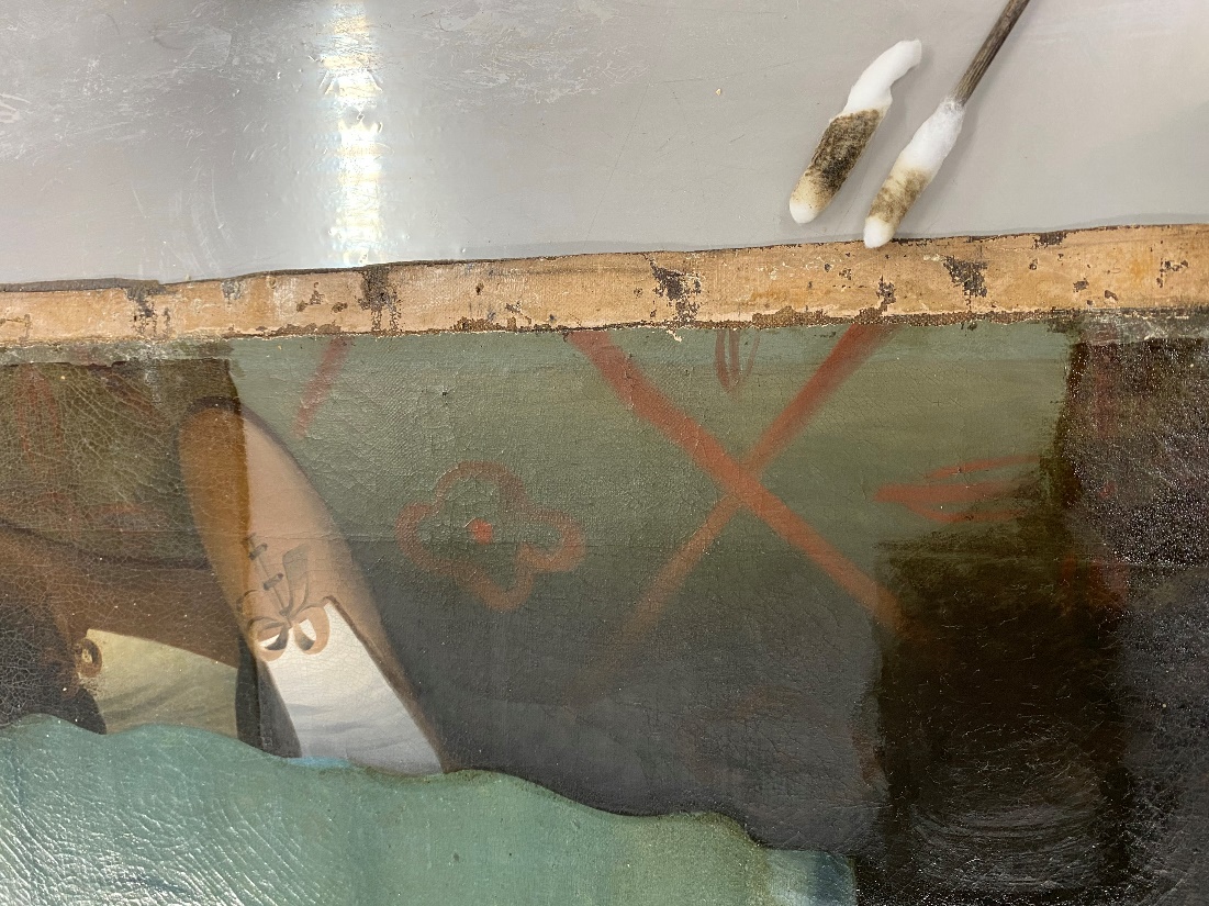 Detail shot of varnish and dirt removal from the floor Bottom of painting canvas showing floor and shoes, with one portion lighter than the remainder; tools nearby