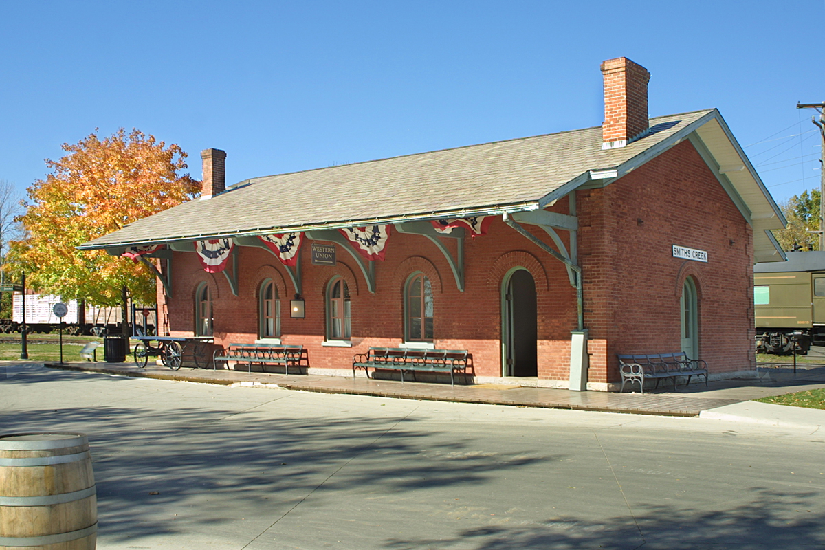 Small brick building with arched windows and decorative eaves and bunting
