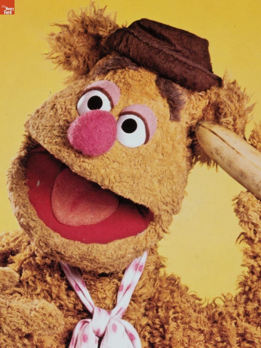 "Jim Henson's Muppets" Lunchbox, 1979 / Fozzie detail Bear puppet wearing brown hat and white scarf with pink polka dots around neck, holding banana to ear