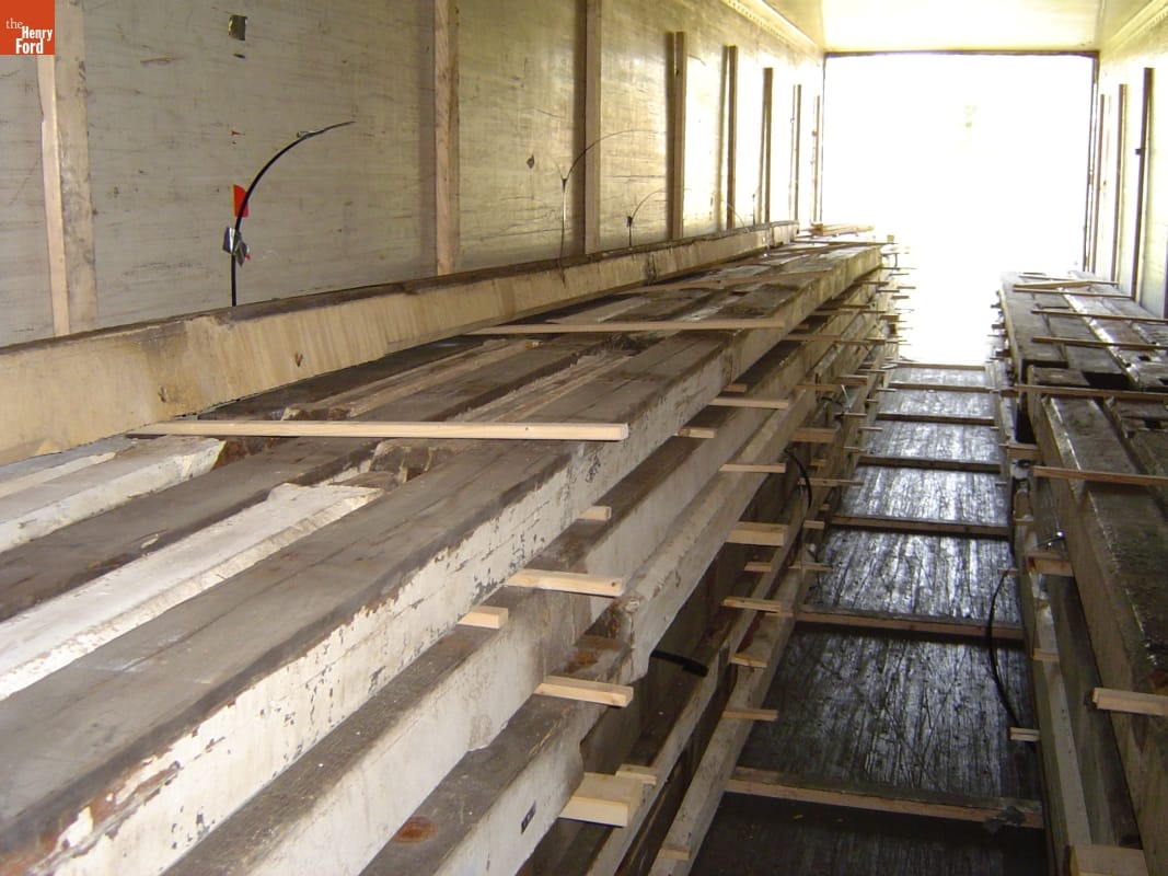 Long, sturdy timbers are carefully stacked in a truck trailer or storage pod