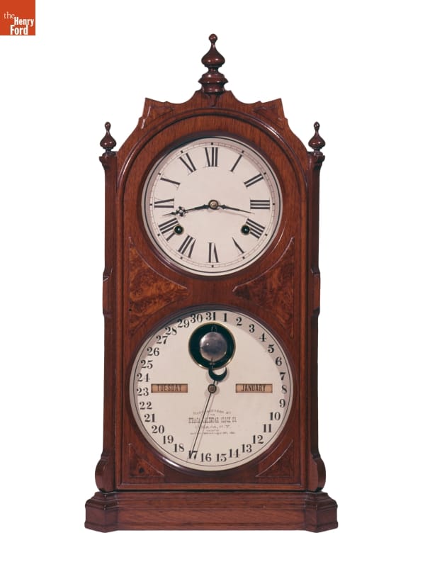 Wooden clock with upper face showing time and lower face showing weekday
