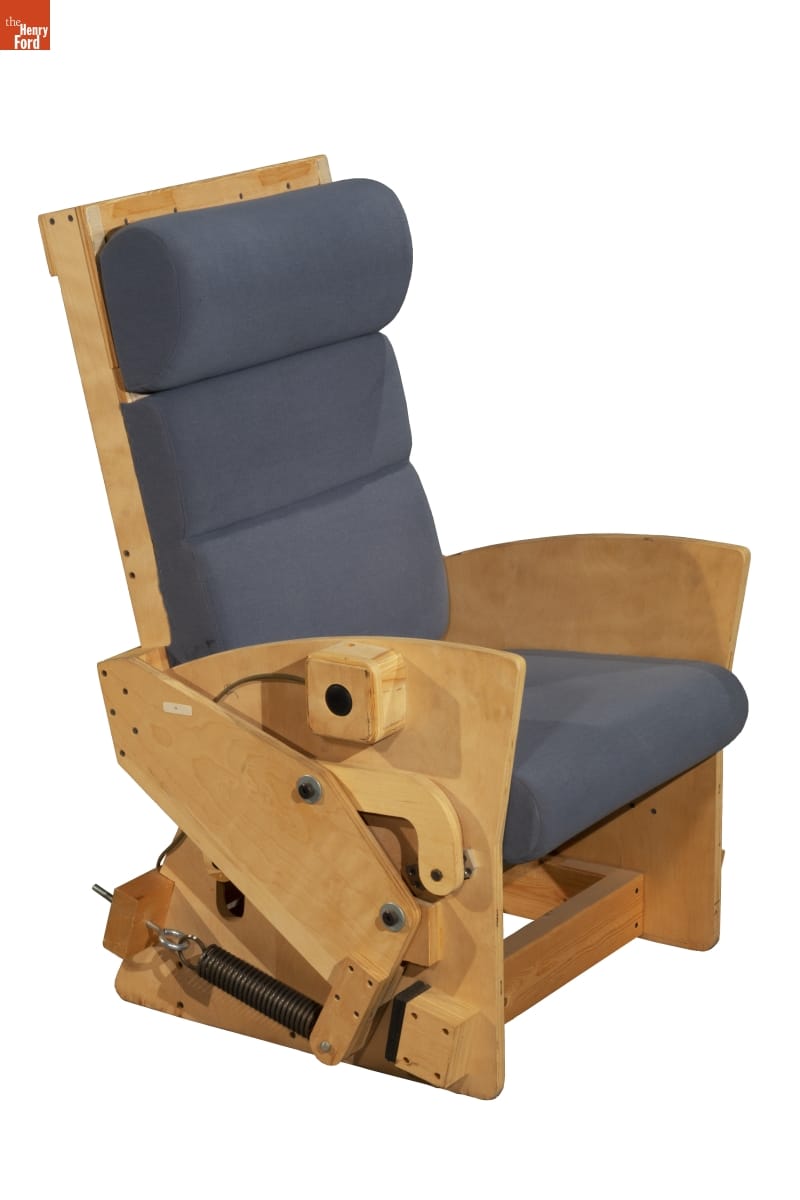 Wooden chair with visible reclining mechanisms on side with steel blue/gray upholstery on seat and seat back