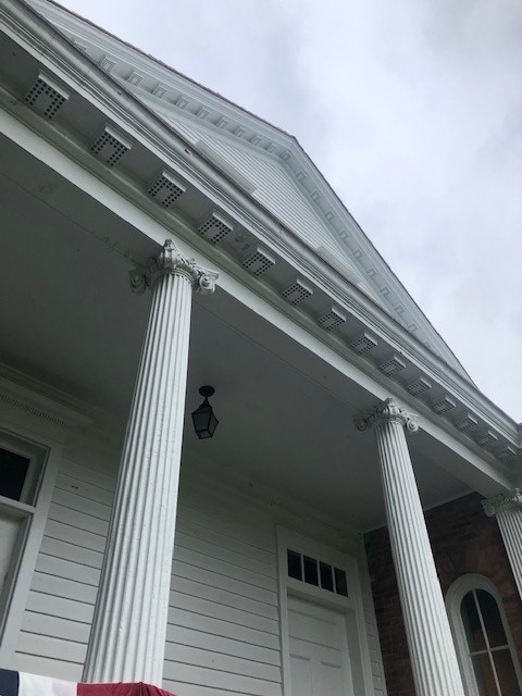 Architectural details of the rear portico of the Noah Webster Home View, looking up from below, of white building porch with columns, topped with triangular gable