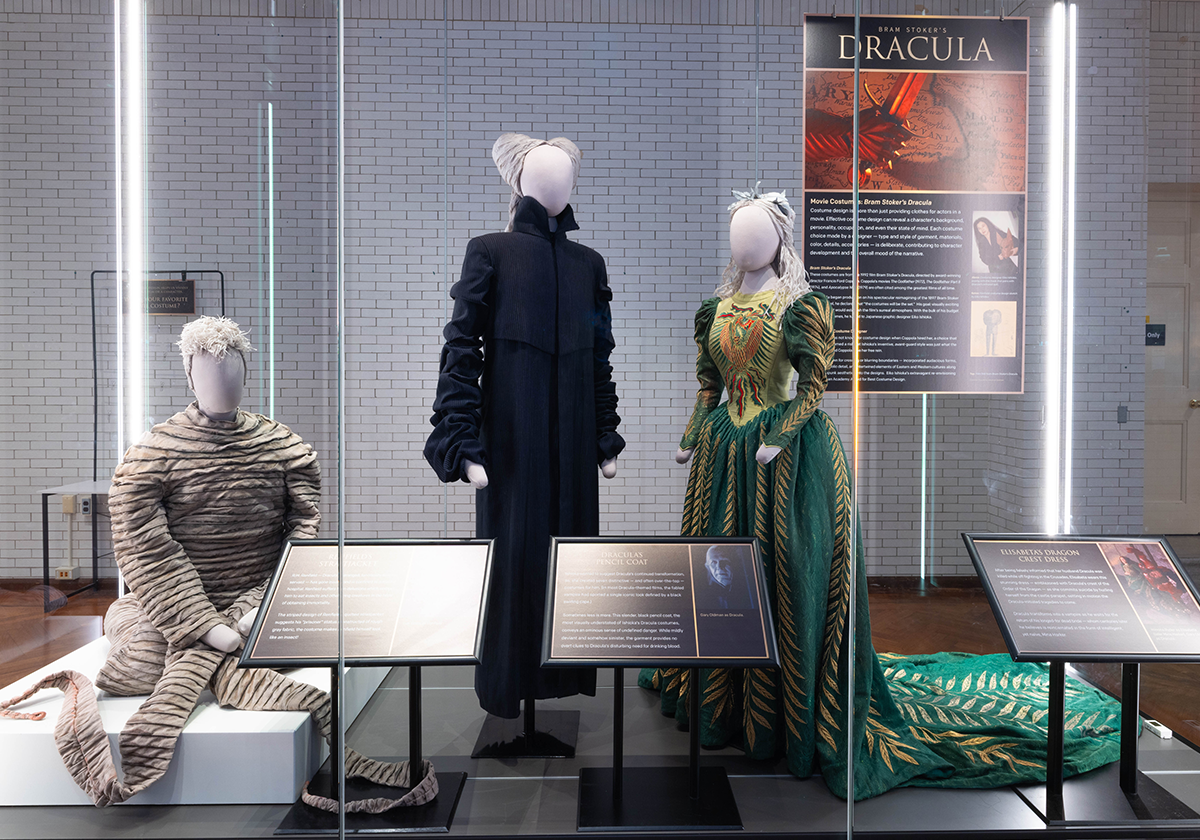 Three mannequins wearing film costumes inside a glss case